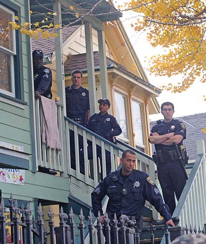 Several uniformed police officers stand on the entry staircase and stare at the cameraperson